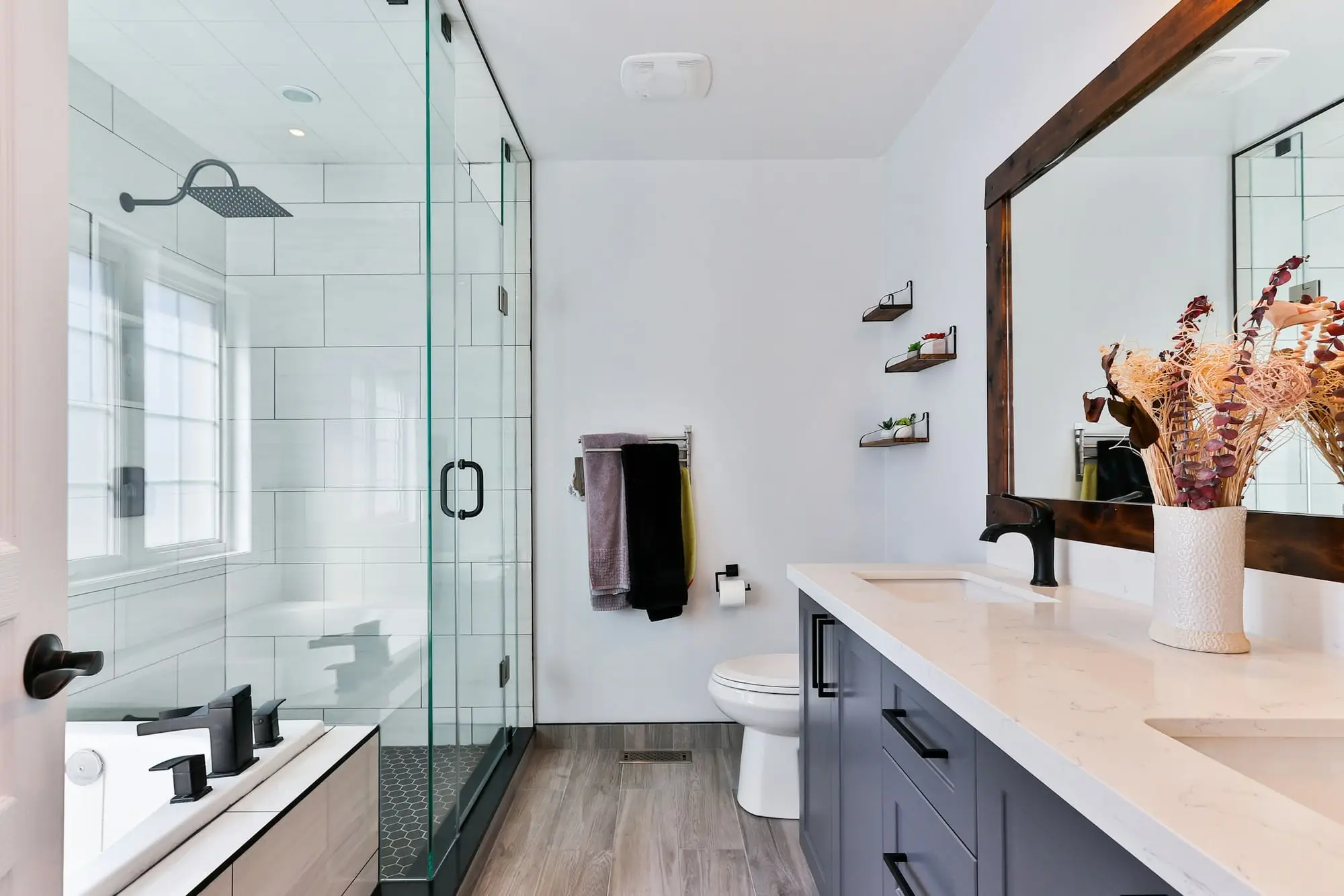 Modern bathroom with a frameless glass shower, white subway tile and a navy vanity with a white countertop